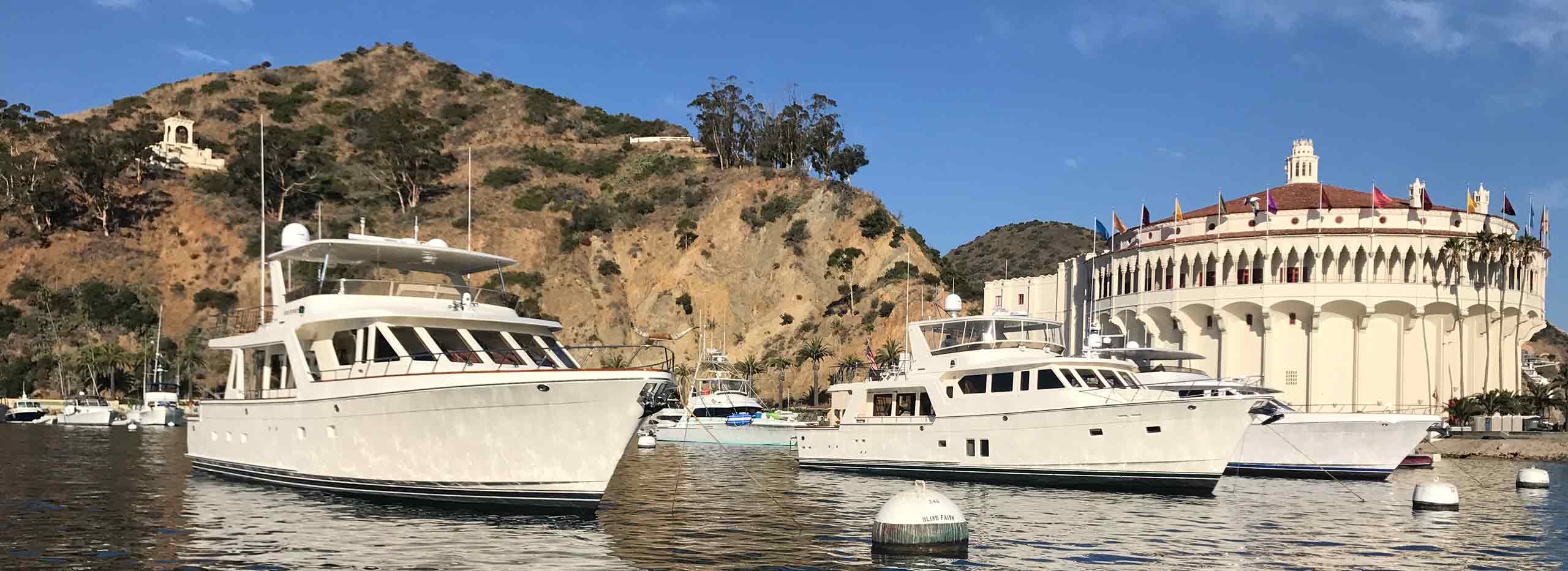 moored offshore yachts against the backdrop of rolling hills